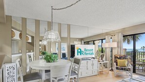 Ett rymligt vardagsrum med matplats, ett stort fönster med fin utsikt och en skylt för uthyrning av semesterbostäder.