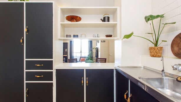 A modern kitchen with black cabinets, white countertops, and a built-in shelf with kitchenware. - Stay OK Central Fremantle (Fremantle)