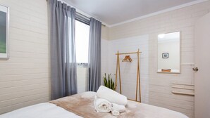 A hotel room with a bed, a wooden hanger, a mirror, and a window with curtains. - Stay OK Central Fremantle (Fremantle)