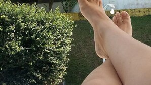A poolside view with a person's legs resting on a white railing, surrounded by greenery and a yellow building. - Country house in Igaratá, standard model, with cable TV, internet, swimming pool, and gourmet area. (IGARATA)