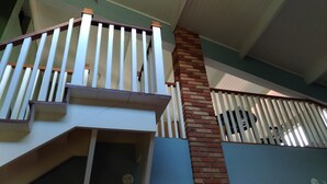 A multi-level interior with a staircase, a brick column, and a white railing. - Country house in Igaratá, standard model, with cable TV, internet, swimming pool, and gourmet area. (IGARATA)