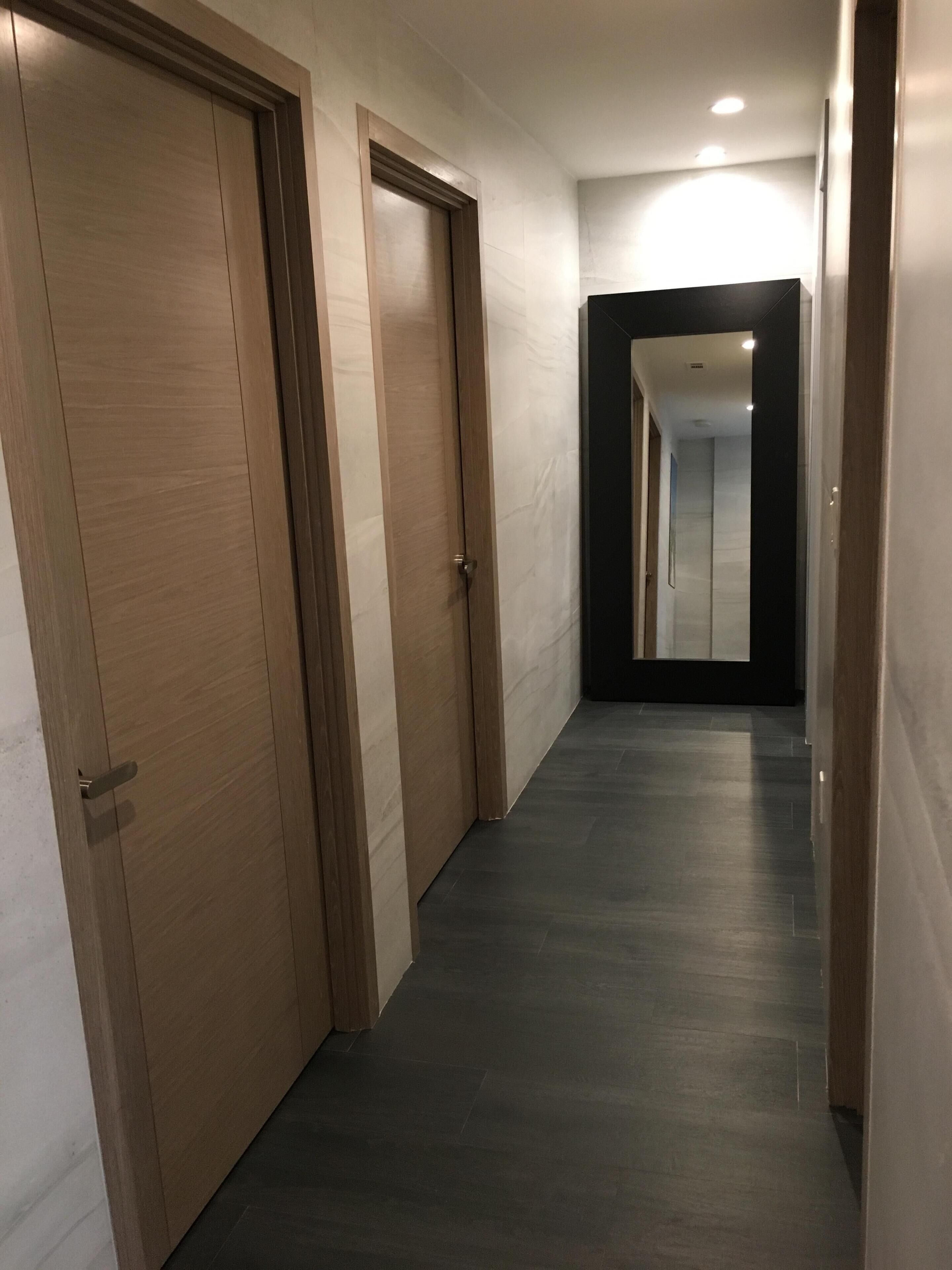 A hallway with wooden doors and a dark floor.