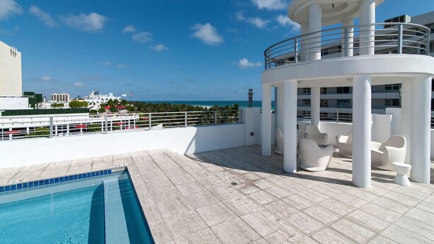 A rooftop pool area with a circular lounge and seating, overlooking a cityscape and ocean. - Miami Beach 3BD Luxury Condo Suite (201) (Miami Beach)
