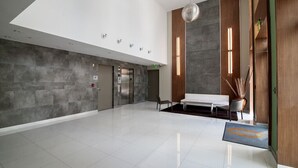 A spacious lobby with a modern design, featuring a large seating area, a reception desk, and a clear view of the elevator. - Miami Beach 3BD Luxury Condo Suite (201) (Miami Beach)