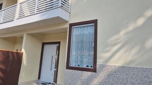 Un edificio con balcón, una puerta y una ventana con cortinas estampadas.