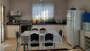Una cocina compacta con una mesa de comedor, sillas, un refrigerador, un microondas y un dispensador de agua.