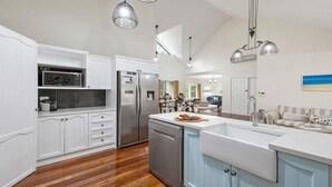 Een moderne keuken met witte kasten, roestvrijstalen apparatuur en een centraal keukenblok met een spoelbak.