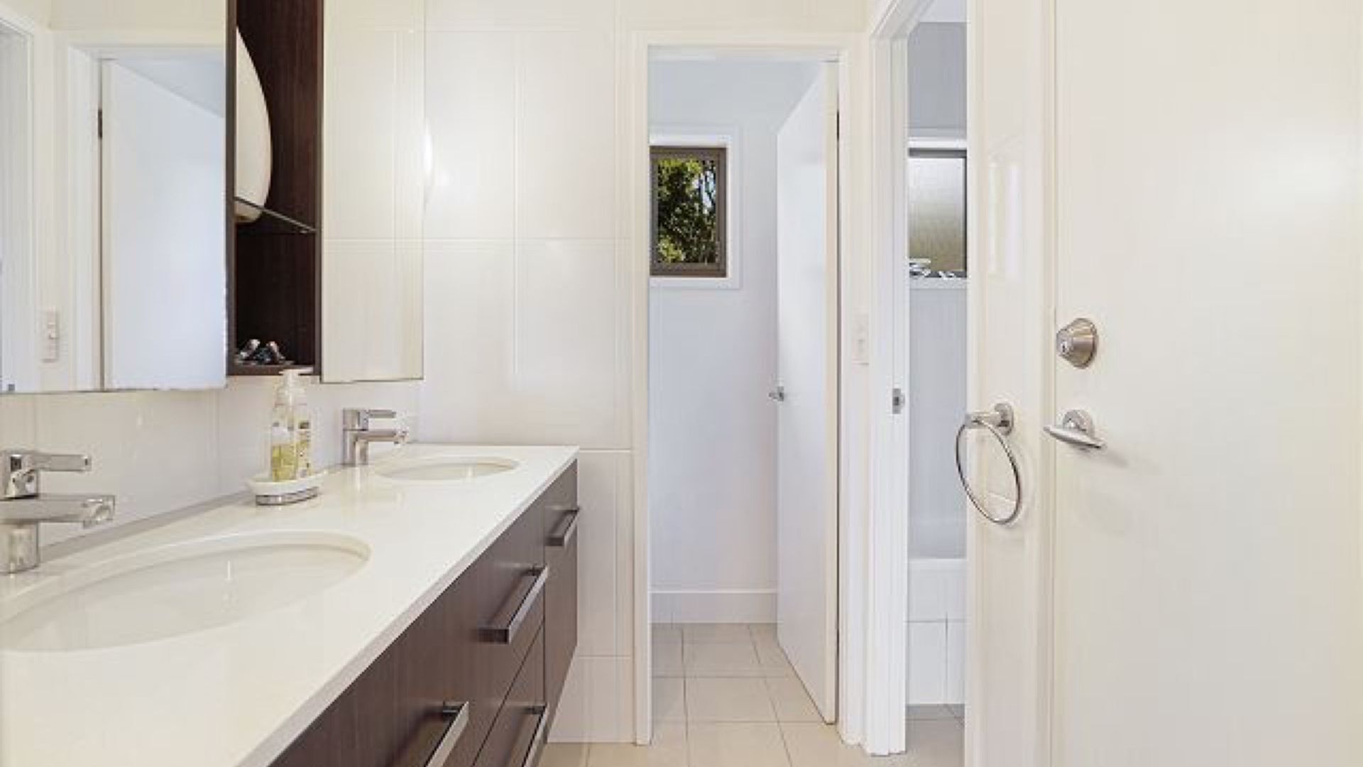 A modern bathroom with two sinks, a large mirror, and a walk-in shower.