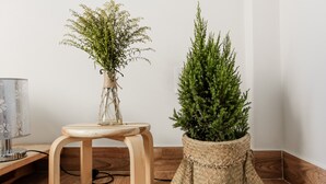 Een hoekje met een houten krukje, een gevlochten plantenpot en een lamp.