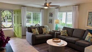 A living room with a brown sofa set, a round coffee table, and a ceiling fan. - Stuart Cottage II Pet Friendly, Remodeled, close to beach and quaint downtown (Stuart)