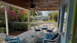 A covered patio with wicker furniture, a table, and chairs. - Stuart Cottage II Pet Friendly, Remodeled, close to beach and quaint downtown (Stuart)