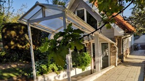 Ein Haus mit überdachter Veranda, einer Ziegel-Fassade und einem kleinen Garten.