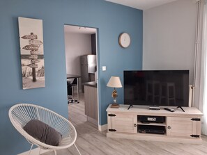 A modern living room with a television, a chair, and a wall-mounted clock.