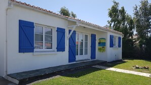 Un bâtiment blanc avec des volets bleus et un toit recouvert de tuiles.