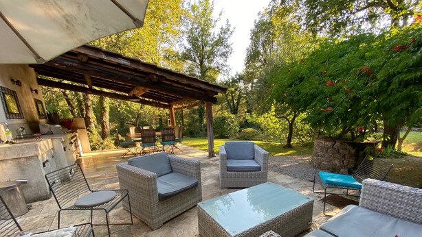 An outdoor patio with wicker furniture, a stone table, and a pergola.