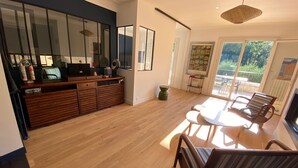 A modern kitchen with a wooden countertop, a dining area with a round table and chairs, and a large window providing a view of the outdoors.