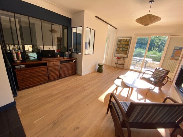 Une cuisine moderne avec un plan de travail en bois, un coin repas avec une table ronde et des chaises, et une grande fenêtre offrant une vue sur l’extérieur.