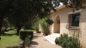A gravel pathway leading to a building with an arched entrance and a window with metal bars.