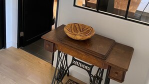 A room with a wooden table, a woven basket, and a sewing machine.