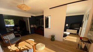 A spacious living area with a wooden floor, a sofa, a coffee table, and a TV.