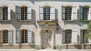 Un edificio con numerose finestre, ognuna dotata di persiane, e una porta centrale con un arco decorativo.