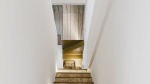 A staircase with beige and brown stone steps leading to a wooden ceiling.
