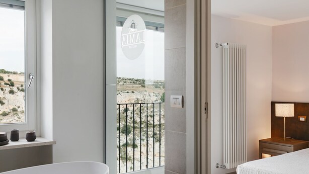 A modern bathroom with a bathtub, a towel, and a view of a desert landscape through a large window.