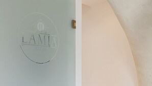 A modern interior with a staircase leading to a higher floor, a light blue wall with a logo, and a white ceiling.