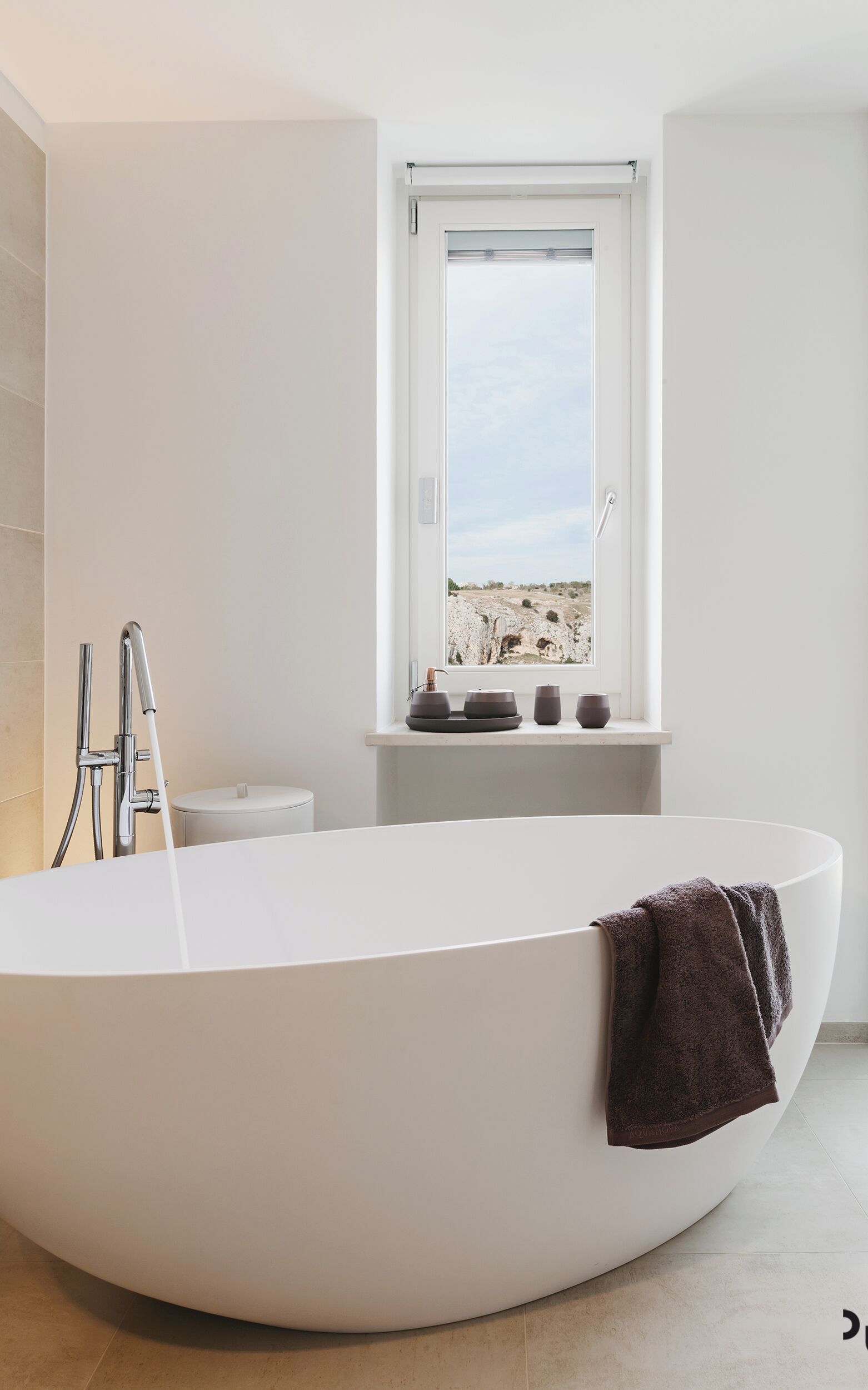 Un baño moderno con una bañera independiente, un ventanal con vistas a un paisaje rocoso y un diseño minimalista.