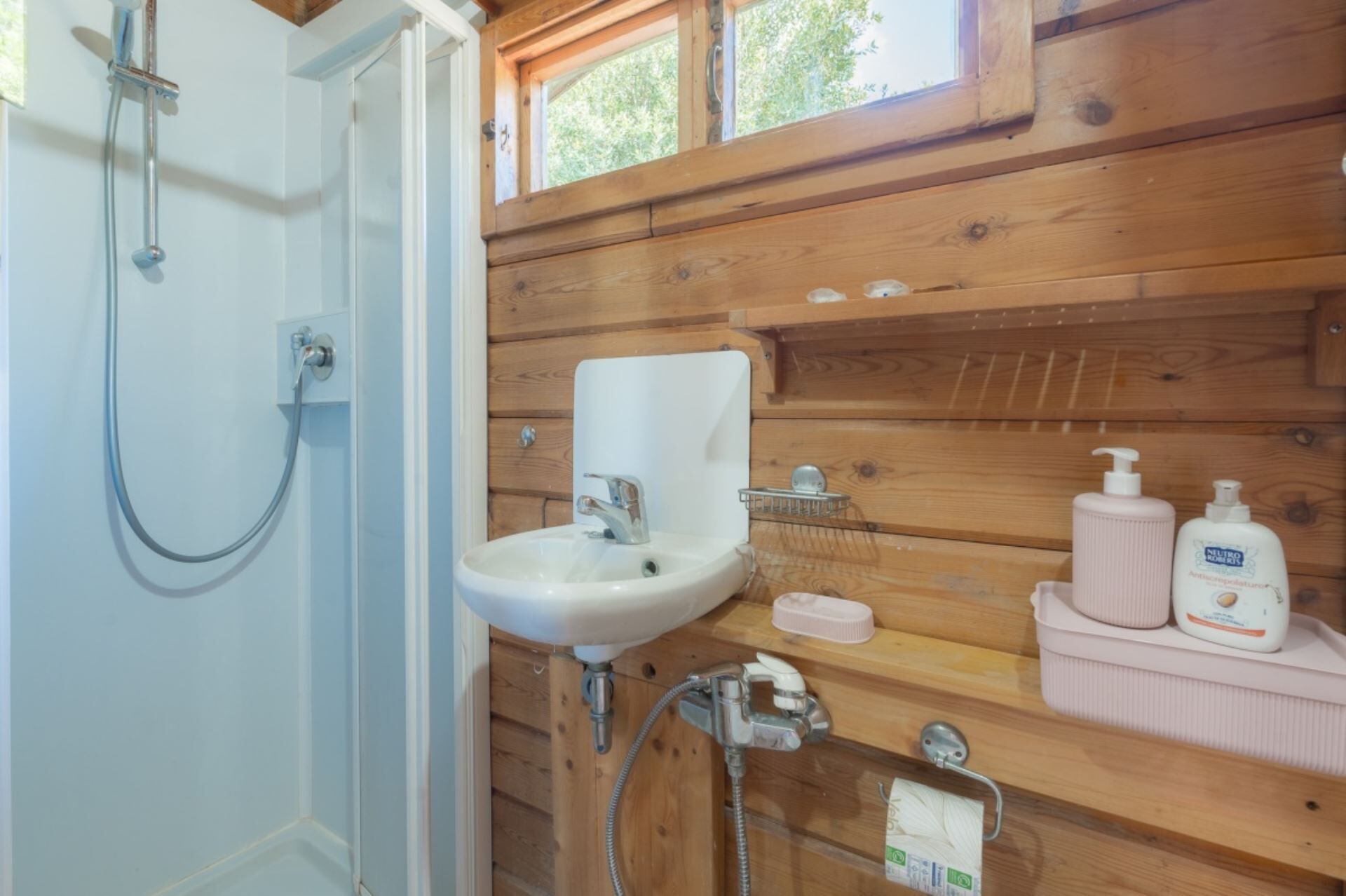 Une salle de bain avec une douche, un lavabo et des murs en bois.
