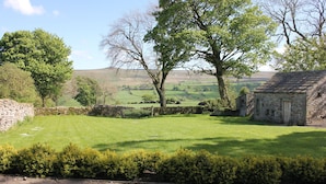A stone building with a thatched roof, surrounded by a well-maintained lawn and mature trees. - Beautiful Grade II listed house with stunning uninterrupted views. Sleeps 8 (Carlton-in-Coverdale, Leyburn, Yorkshire)