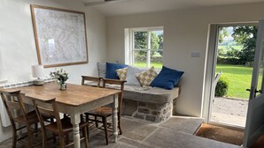 A dining area with a wooden table and chairs, a stone bench with cushions, and a large map on the wall. - Beautiful Grade II listed house with stunning uninterrupted views. Sleeps 8 (Carlton-in-Coverdale, Leyburn, Yorkshire)