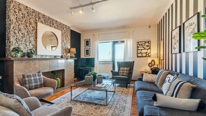 Ein Wohnzimmer mit Kamin, Streifenoptik und einer Sofagarnitur.