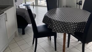 Ruokailutila, jossa on pyöreä pöytä, jonka päällä on pilkkukuviollinen pöytäliina, ja pöydän ympärillä on mustia tuoleja.