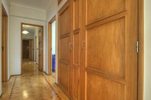 Enter a beautifully appointed hallway with herringbone-patterned floors and wooden paneling.
