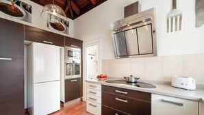 Una cocina moderna con refrigerador, horno, microondas y un fregadero con una olla sobre la encimera.
