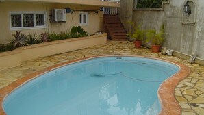 A swimming pool with a tiled deck, surrounded by potted plants and a staircase leading to an upper level. - Magnificent sea and mountain views from the roof terrace. Quiet and restful place (Morc. Anna, Flic en Flac)