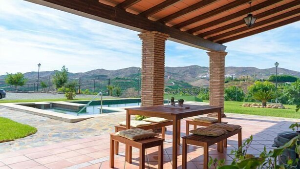 Une terrasse extérieure avec une piscine, des meubles en bois et une vue sur les montagnes.