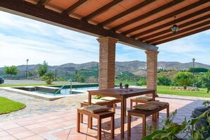 An outdoor patio with a pool, wooden furniture, and a view of mountains. - Casa Rural Villa Solgor for 6 people (Benamocarra)