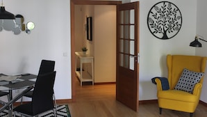 Una sala de estar moderna con comedor, un sillón amarillo y una obra de arte en la pared.