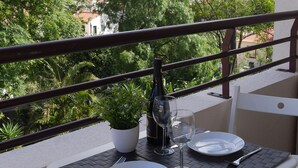 Un balcón con una mesa dispuesta para dos personas, con vistas a un paisaje urbano que incluye un castillo histórico.