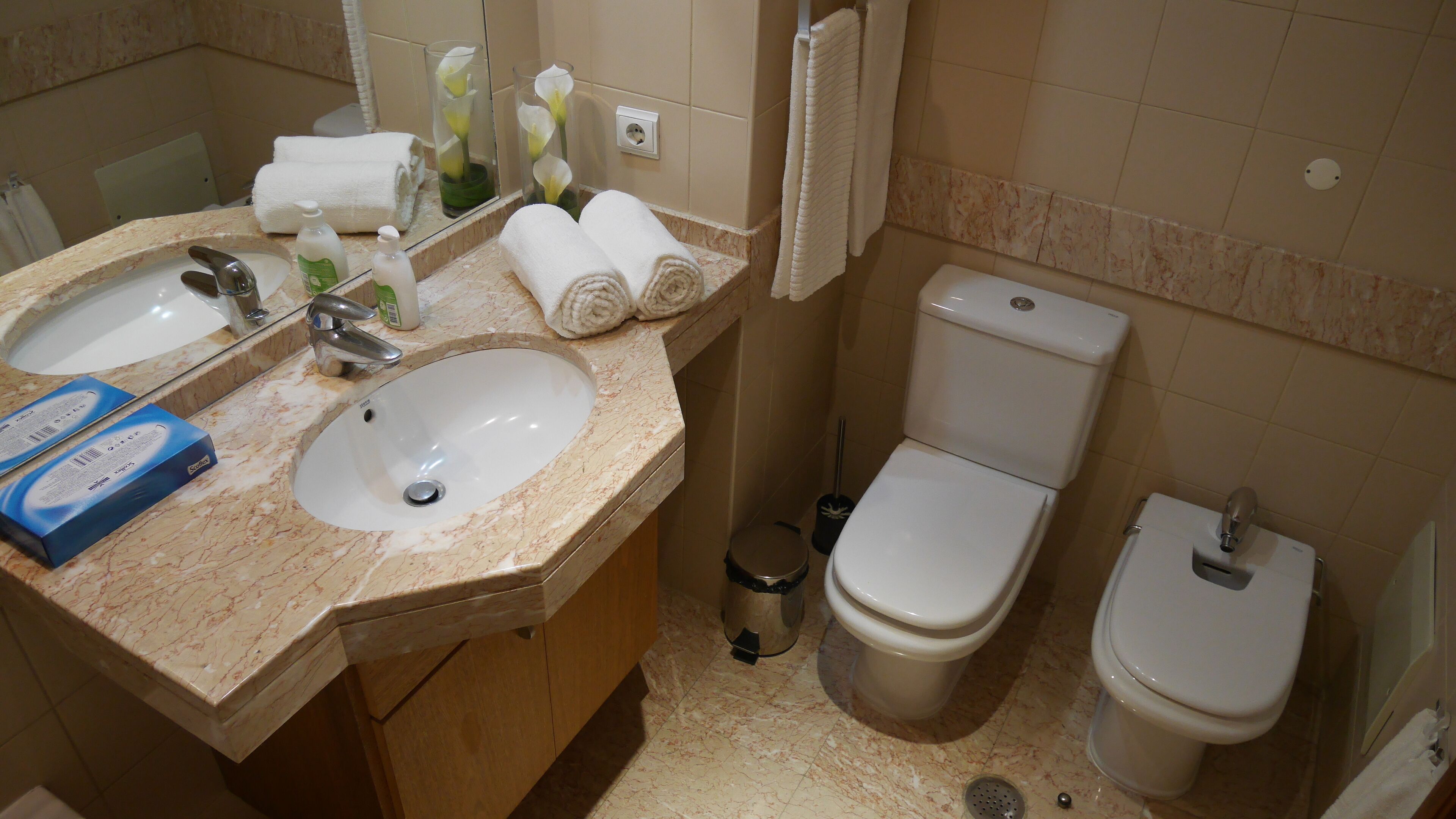 Ein Badezimmer mit zwei Waschbecken, einer Toilette und einem Mülleimer.