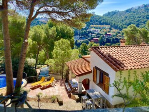 Una villa con techo de tejas, piscina y zona de estar exterior.