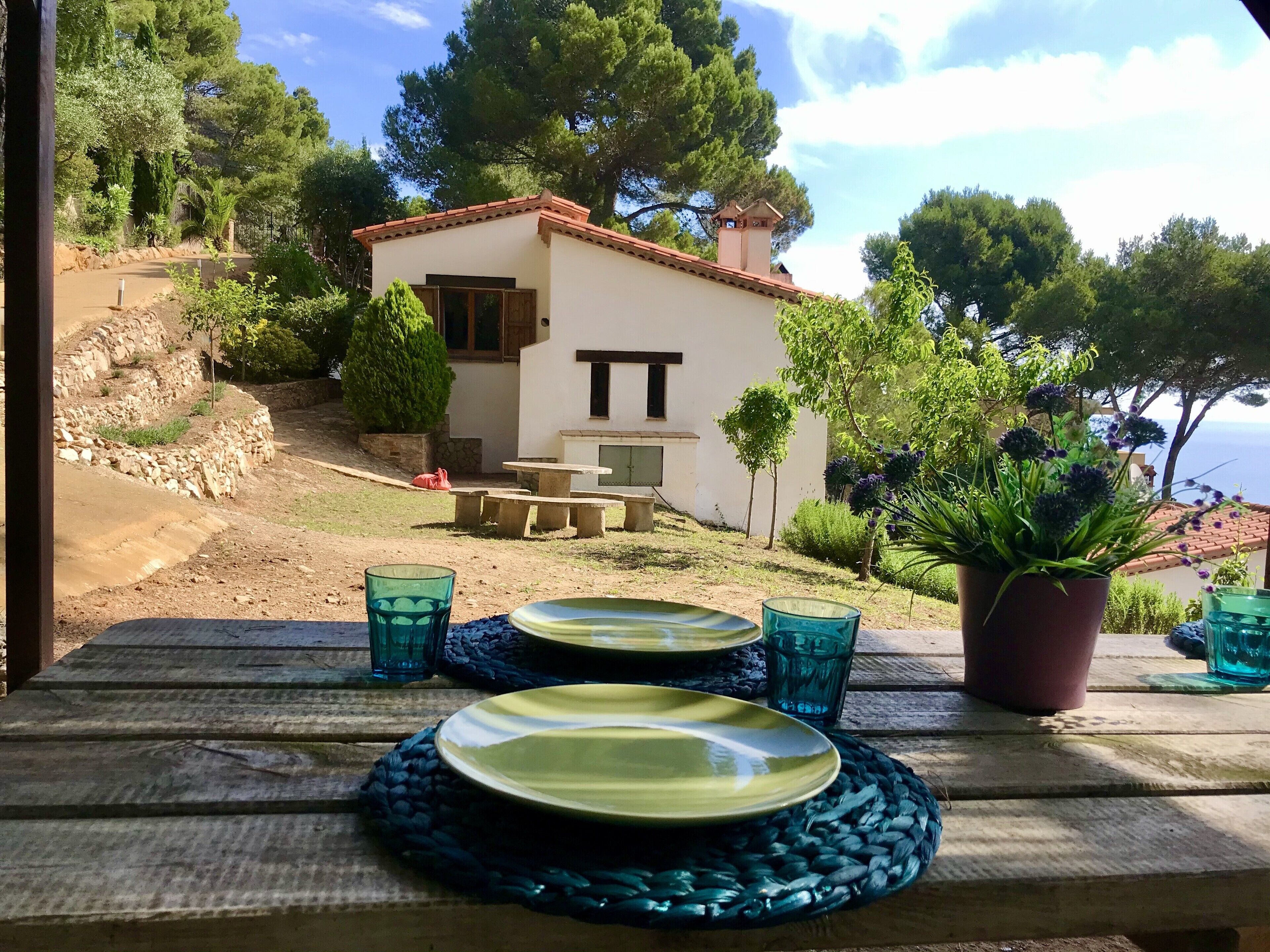 A rustic outdoor dining area with a stone wall, a small table, and a potted plant.
