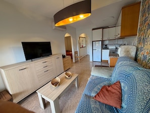 Een moderne woonkamer met een televisie, houten meubels, een bankje en een gestreept sofa.
