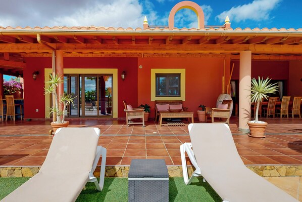 Un espacio de descanso al aire libre con sillones, una mesa y plantas en macetas.