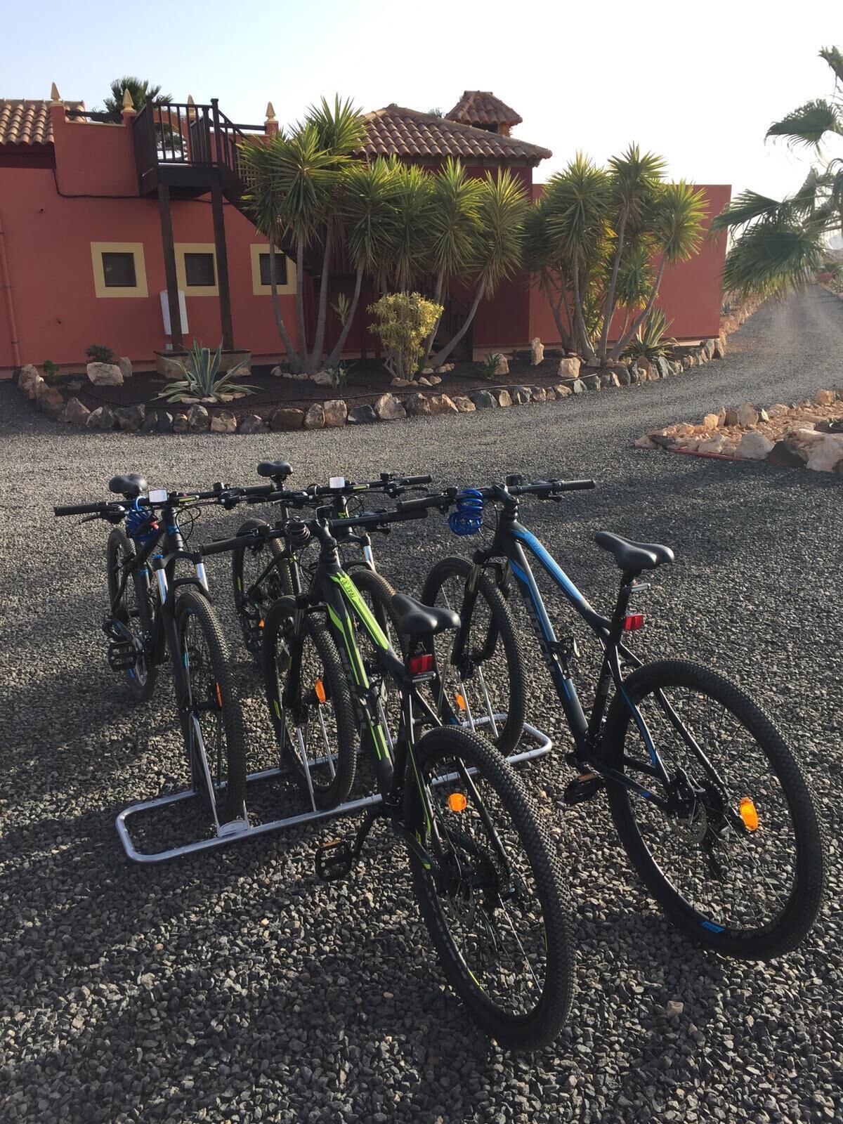 A gravel parking area with bicycles parked on a rack.