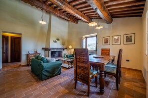 Un intérieur rustique avec une cheminée, une table à manger en bois et un canapé vert.