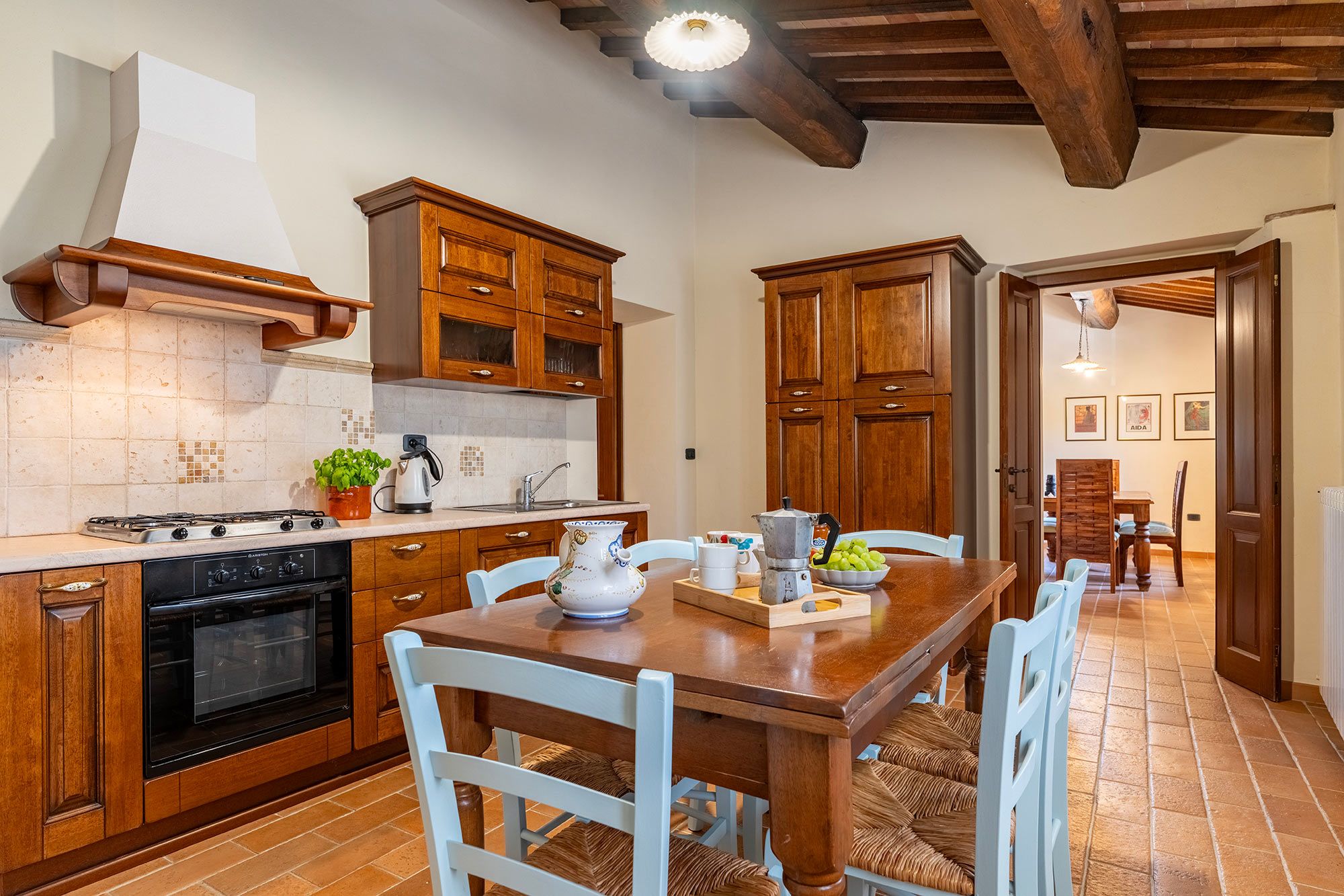 Una cocina con armarios de madera, una estufa y un comedor con mesa y sillas.