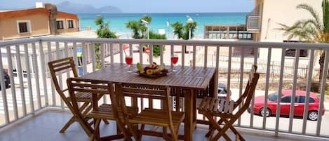 A wooden table with chairs on a balcony overlooking the sea.